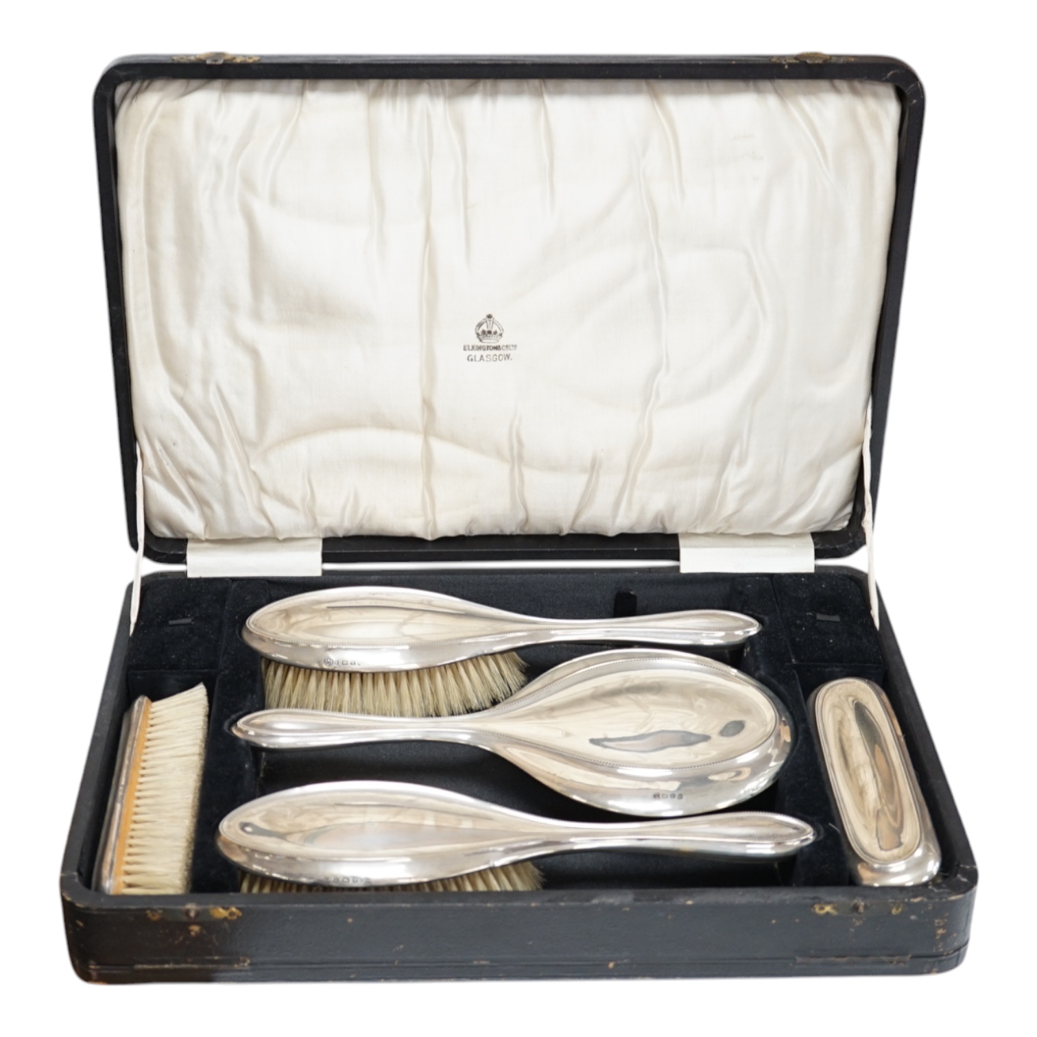 A cased George V five piece silver mounted dressing table mirror and brush set, Charles S. Green & Co, Birmingham, 1920/21. Condition - fair